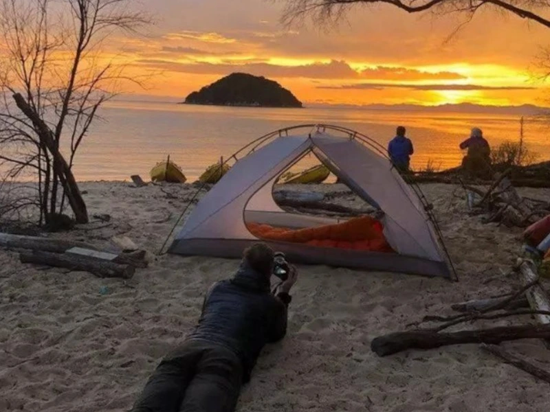 Zelt am Strand bei Sonnenuntergang im Abel Tasman Nationalpark, Neuseeland