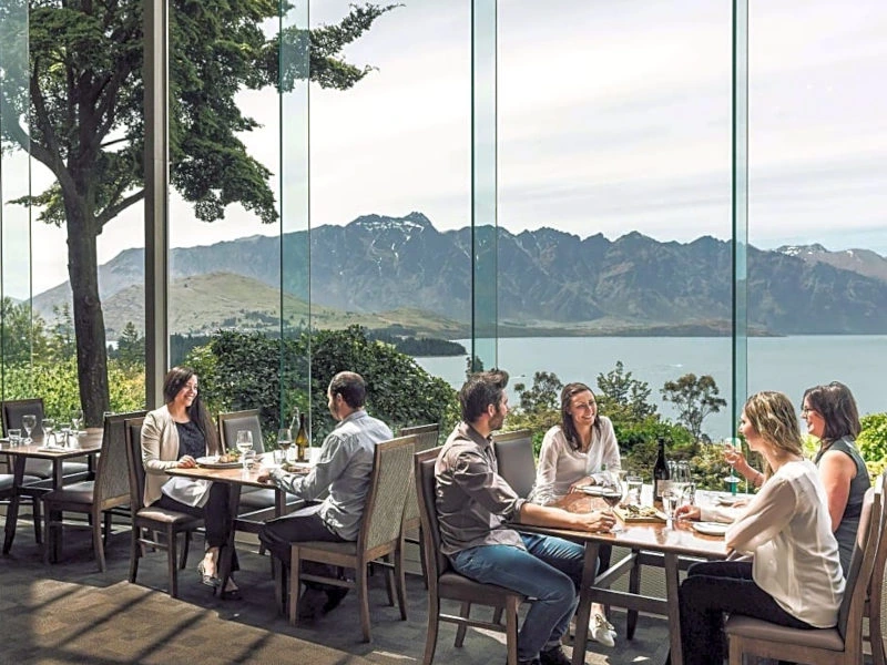 Menschen beim Essen im Restaurant mit Blick auf Queenstown, Gruppenreise Neuseeland