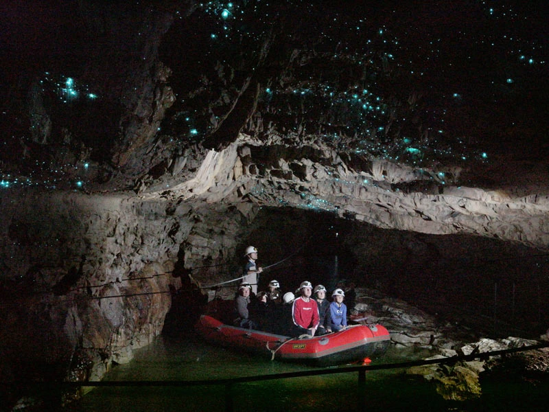 Personen fahren im Schlauchboot durch die Glühwürmchenhöhlen in Waitomo, Neuseeland