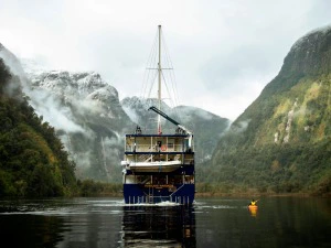Kajak fährt neben einem großen Schiff im Doubtful Sound in Neuseeland.