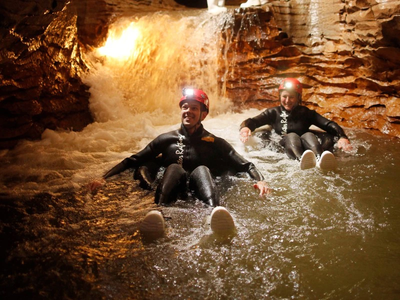 Personen schwimmen im Reifen durch eine Höhle in Waitomo, Neuseeland