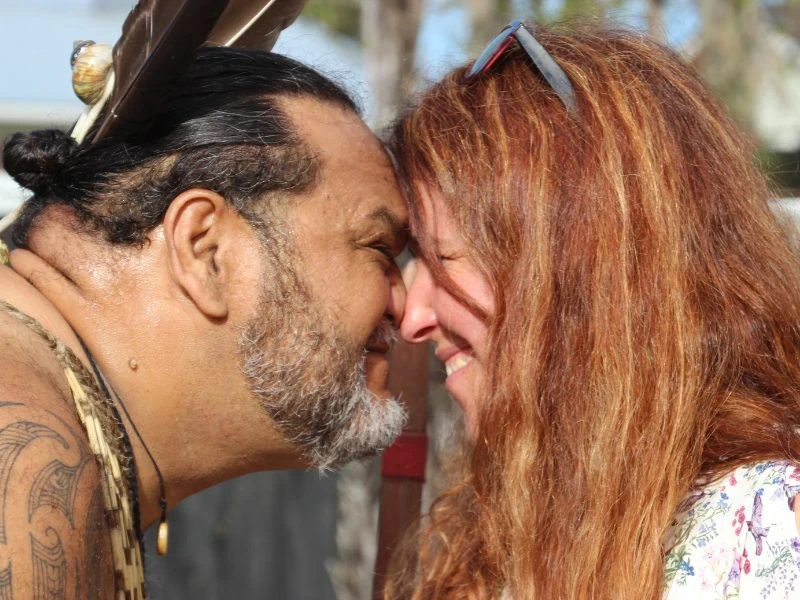 Frau wird auf traditionelle Weise von einem Maori begrüßt in Neuseeland.