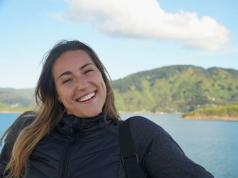 Frau posiert lächelnd auf der Fähre von Wellington nach Picton in Neuseeland.