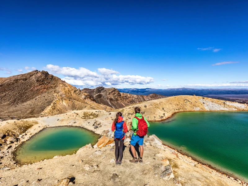Personen blicken in die Landschaft und auf die Seen im Tongariro Nationalpark, Neuseeland.