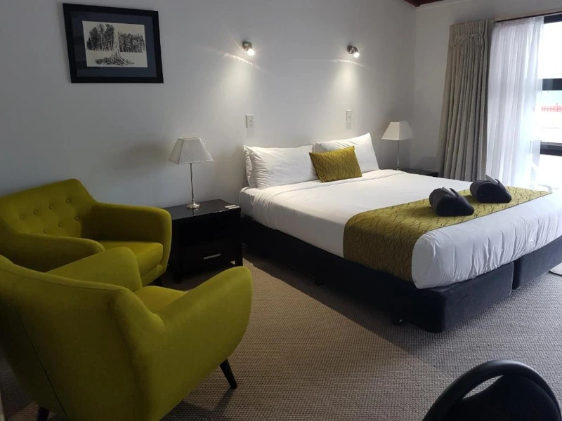 Hotelzimmer mit gemütlichem Bett und Sesseln in der Gletscher Region in Neuseeland