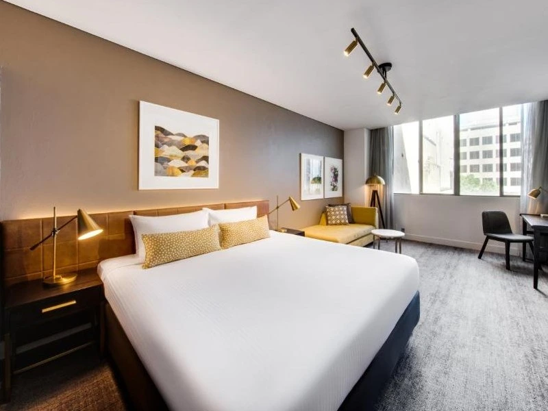 Helles Hotelzimmer mit Bett, Schreibtisch und Recamiere