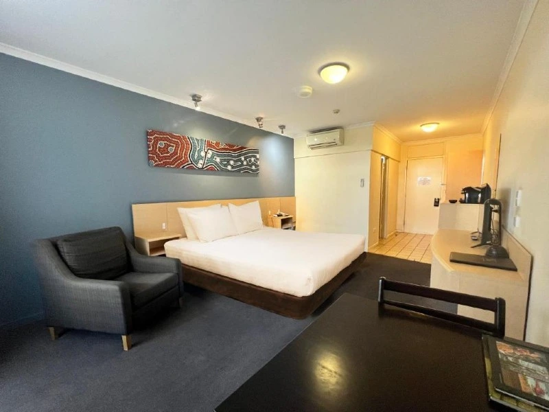 Großzügiges Hotelzimmer mit Bett, Sessel und Tisch mit Stühlen