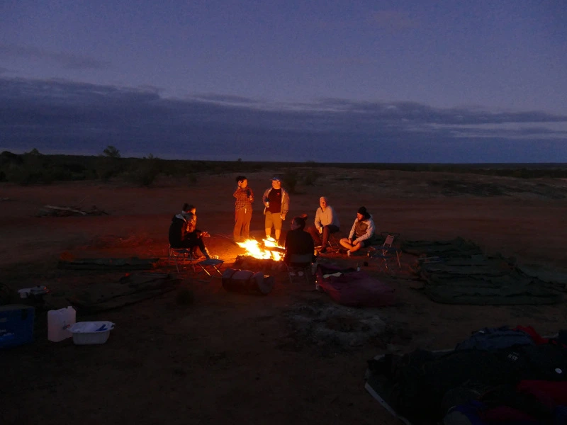 Gruppe sitzt am Lagerfeuer auf Campingtour im Outback, Campingtour