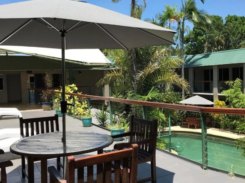 Tisch mit Stühlen unter dem Sonnenschirm mit Blick auf Hotelpool