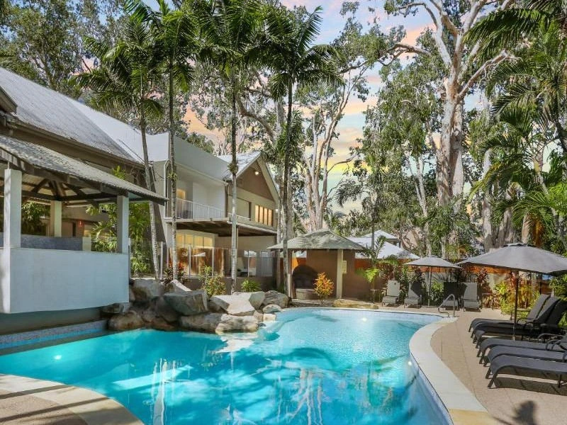Pool mit Liegen und Palmen im Hintergrund