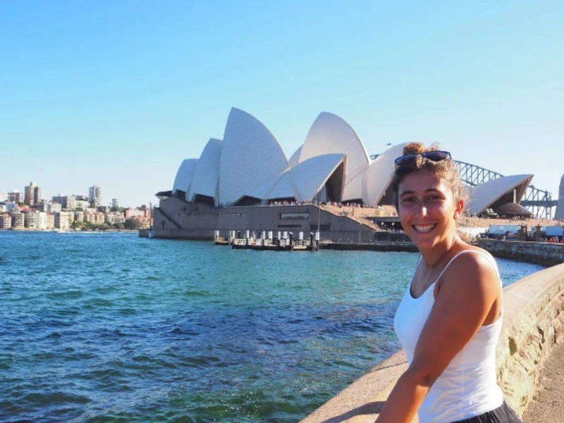 Frau posiert vorm Opernhaus in Sydney, Australien.