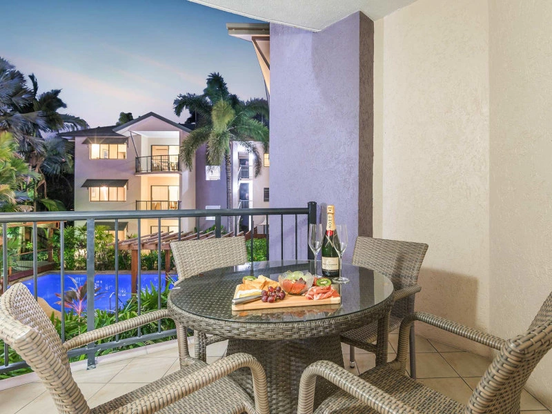 Snacks und Drinks stehen auf dem Balkontisch mit Blick auf den Pool im Hotel in Port Douglas, Australien.
