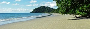 Australischer Strand mit weißen Sand, blauen Himmel und etwas grüne Natur