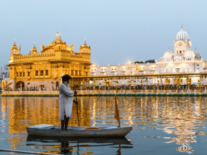 Einheimischer auf einem Ruderboot vor dem goldenen Tempel in Amritsar, Indien