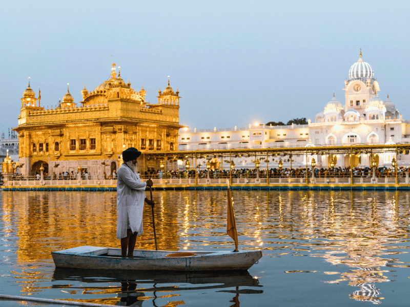 Einheimischer auf einem Ruderboot vor dem goldenen Tempel in Amritsar, Indien