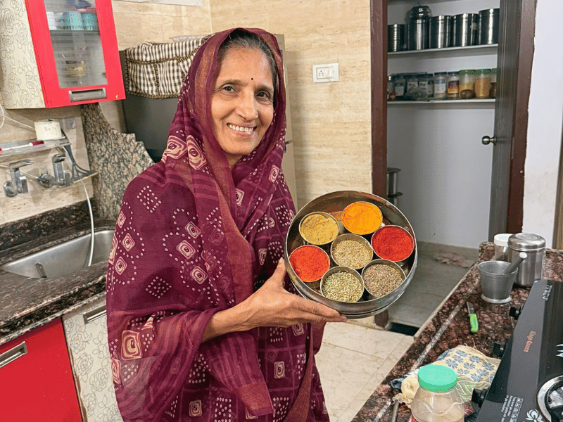 Einheimische Frau mit Gewürzen beim Kochkurs in Indien