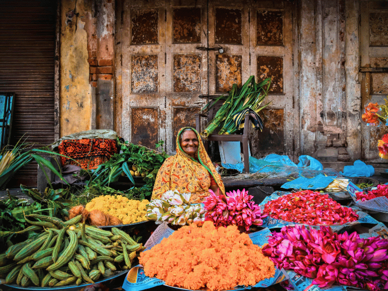 Händlerin auf Markt mit Blumen und Gemüse in Indien