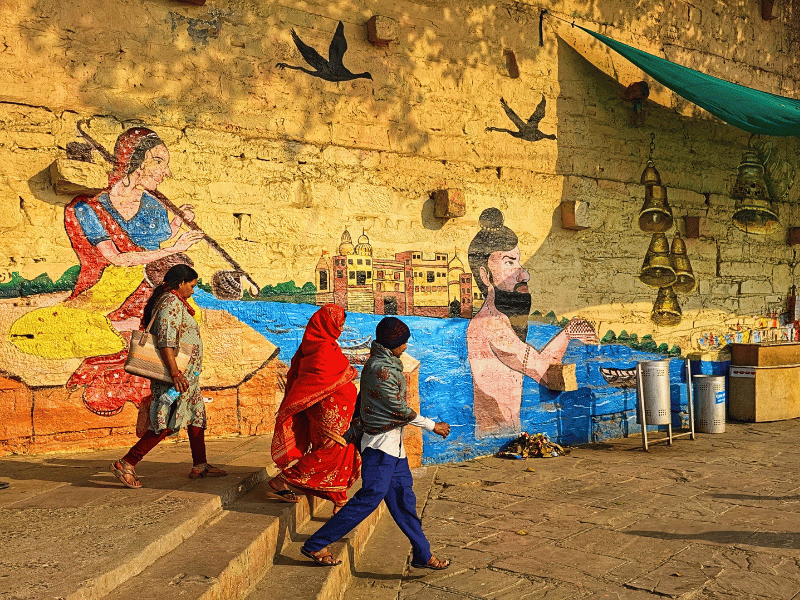 Einheimische vor einer Mauer mit Streetart in Varanasi