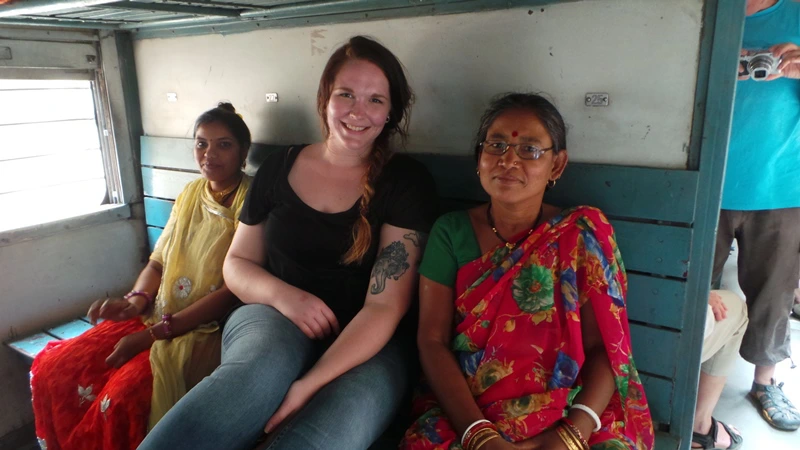 Reisende zwischen Inderinnen auf der Zugfahrt nach Deogarh in Indien