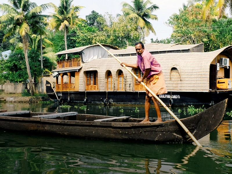 Mann lenkt ein Boot auf dem Fluss in Kerala in Indien