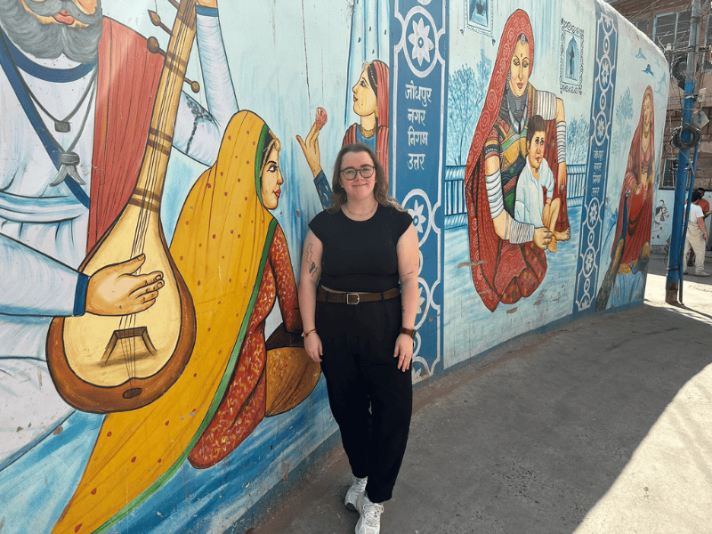 Frau vor kunstvoller Grafitti Wand in Indien