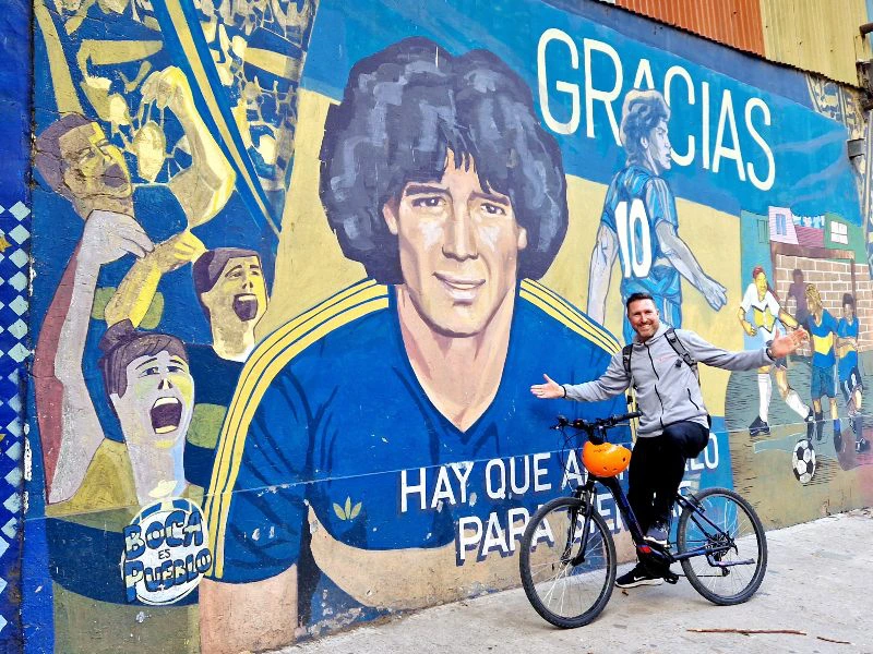 Reisender auf einem Fahrrad vor Wandgraffiti von Diego Maradonna in Buenos Aires in Argentinien