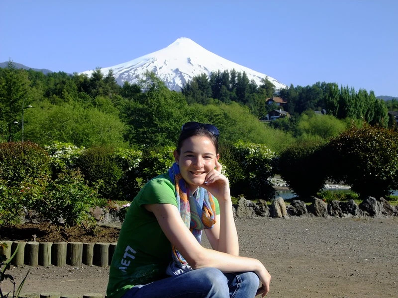 Reisespezialistin Mara sitzt vor dem Pucon Vulkan in Chile