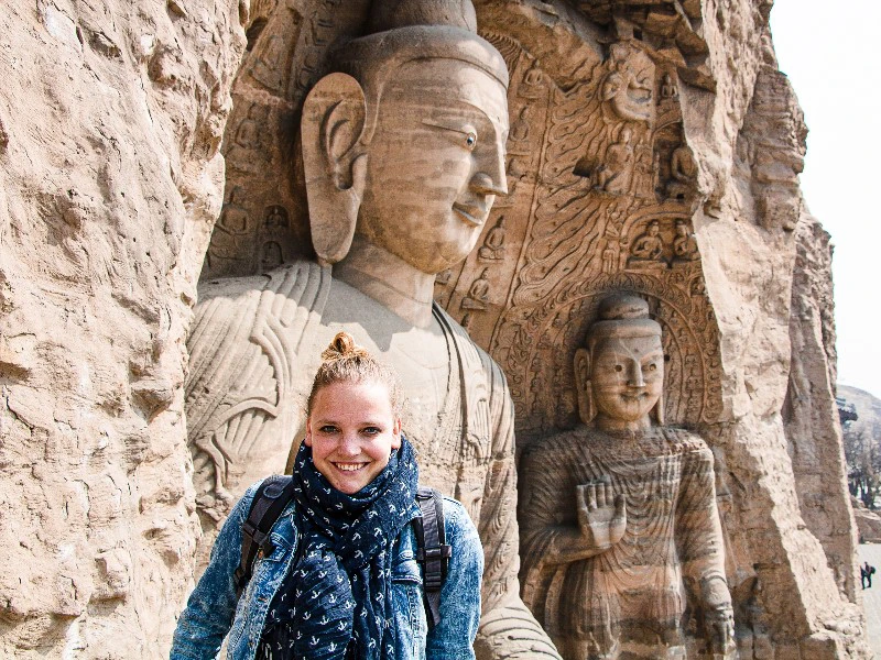 Reisende vor der großen Buddhastatue in den Longmen Grotten in Luoyang