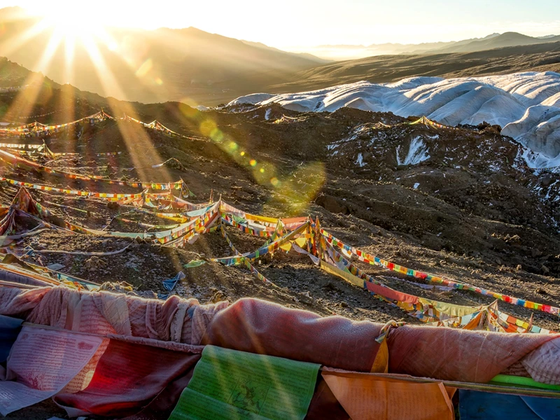 tibetische Gebetsfahnen und Handtücher am Hang im Himalaya Gebirge in Tibet, China bei Sonnenuntergang