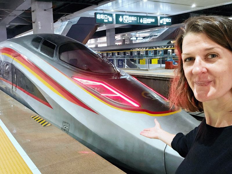 Touristin posiert vor einem Hochgeschwindigkeitszug in China