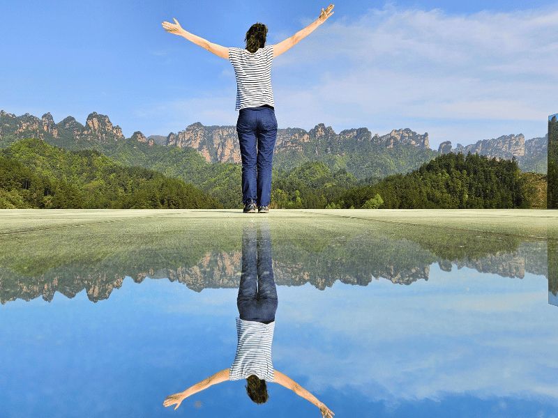 Vrouw poseert op glazen brug met bergen op de achtergrond