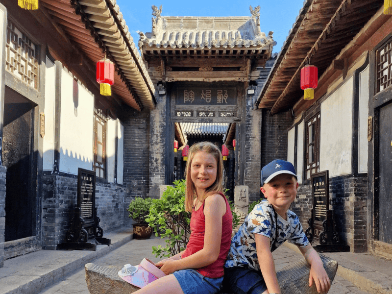 Kinder sitzen vor einem Tempel in Pingyao