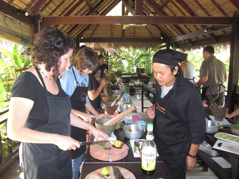 Touristen mit Utensilien beim Kochkurs in Laos