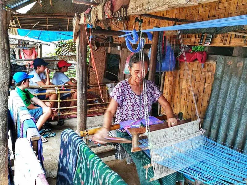 Frau an einem Webstuhl in einem Dorf in Laos