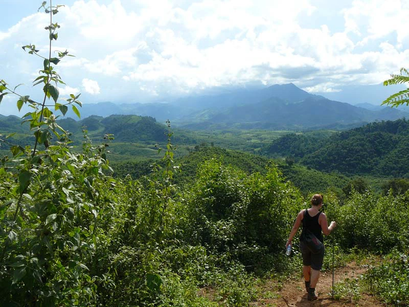 Tourist vor grünen Hügeln und weiter Landschaft in Laos