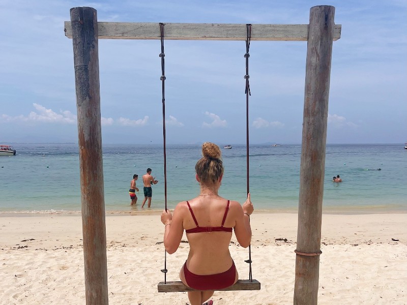 Tourist sitzt auf einer Schaukel am Manukan Island Strand