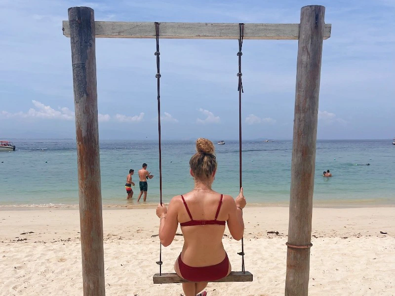 Tourist sitzt auf einer Schaukel am Manukan Island Strand