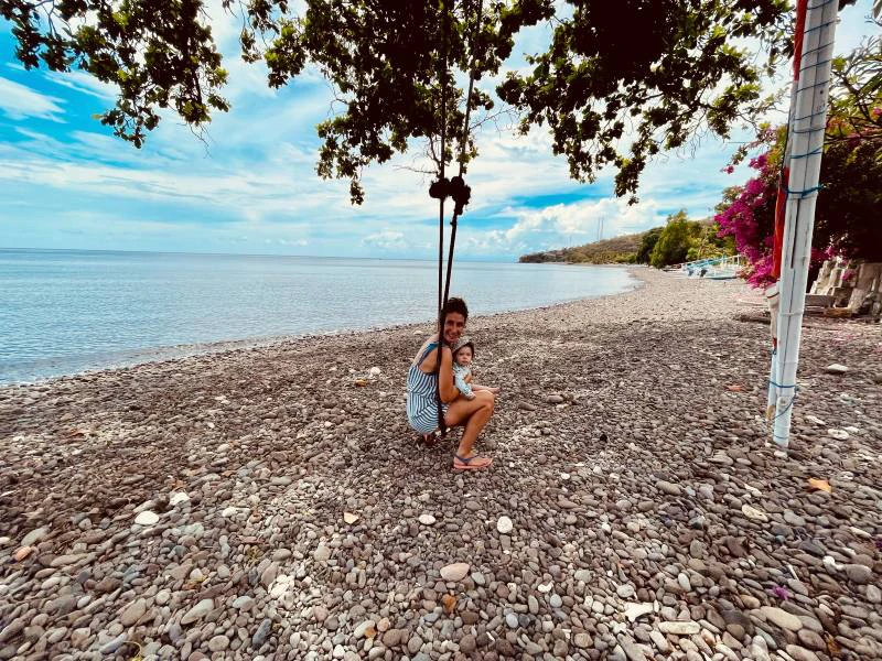 Kind am Steinstrand auf einer Schaukel bei Amed auf Bali