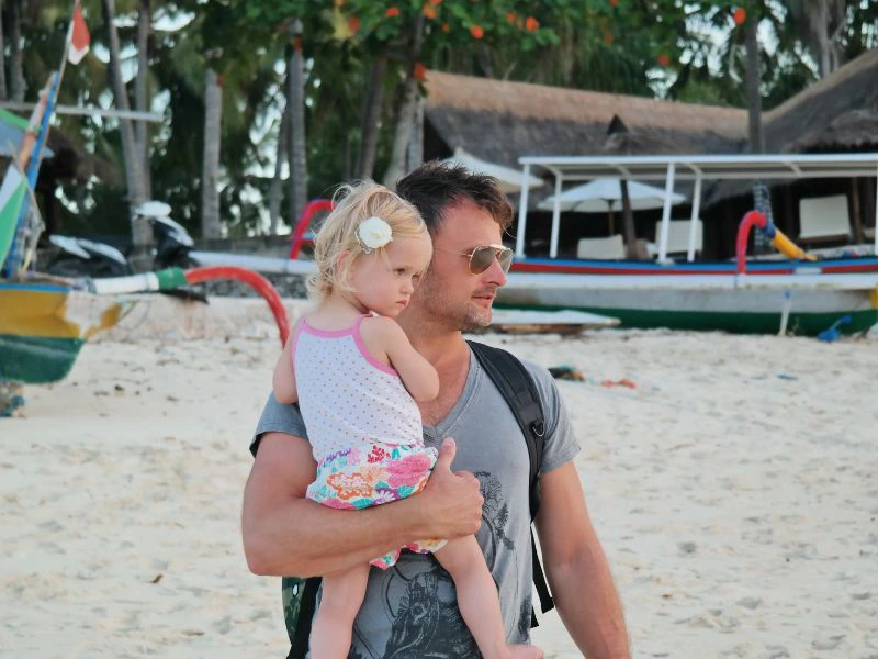 Reisender mit Kind auf dem Arm in Benoa auf Bali