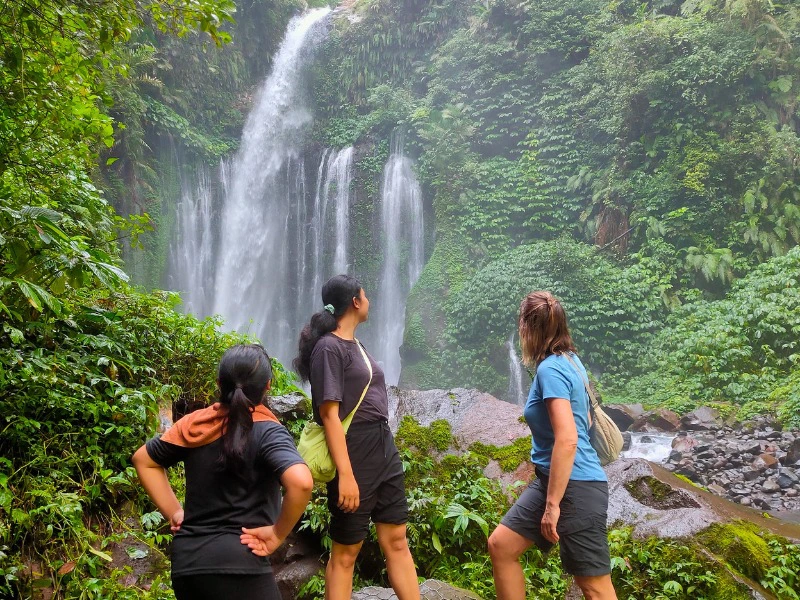 Reisende vor einem Wasserfall bei Senura auf Lombok