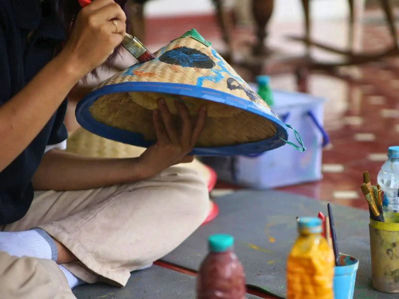 Tourist bemalt Hut mit Batik bei einem Workshop in Indonesien