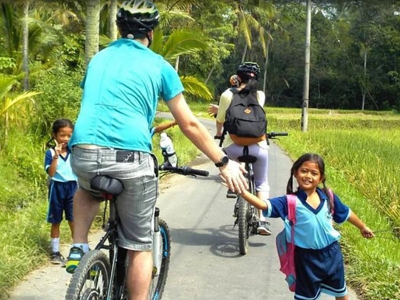 Fahrradfahrer grüßt einheimisches Kind auf Lombok