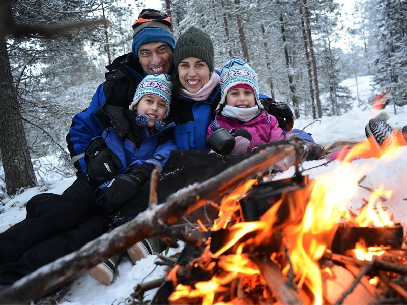 Familienfoto am Feuer im Schnee in Lappland