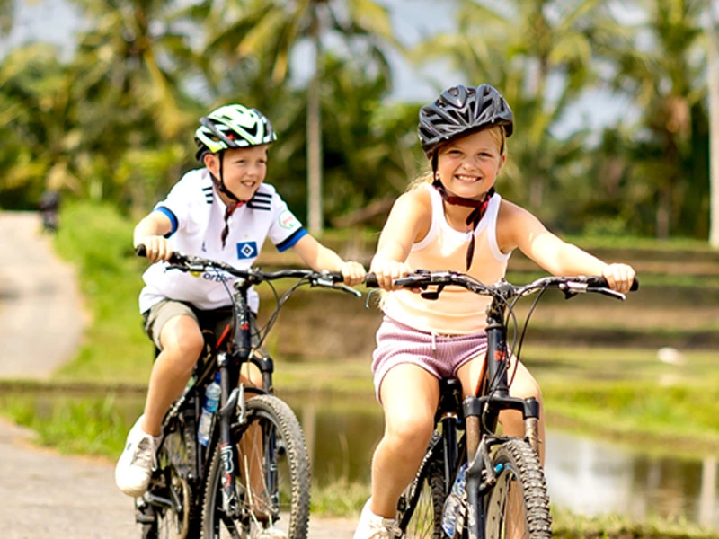 Geschwister fahren mit dem Rad durch die Reisfelder auf Bali