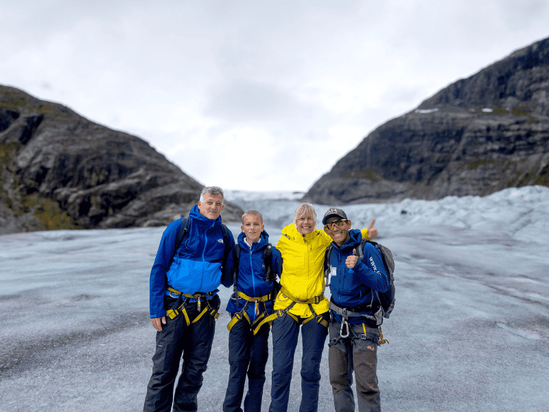 Familie steht mit einem lokalen Guide an einem Gletscher
