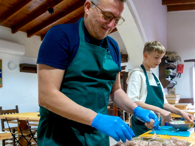 Vater und Sohn in dunkelgrünen Schürzen bei einem Kochkurs
