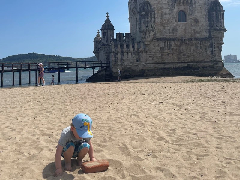 Buddeln im Sand vor dem Torre de Belem, Portugal