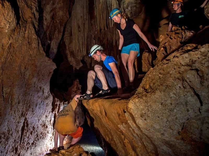 Reisende mit Helm klettern durch eine Höhle.