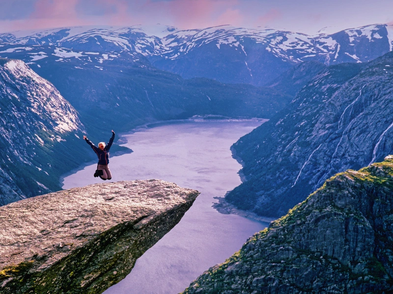 Ein Mensch springt auf einer Felszunge in die Luft