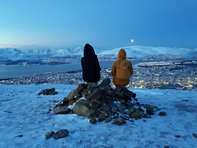Zwei Menschen von hinten blicken im Winter auf eine Stadt hinunter